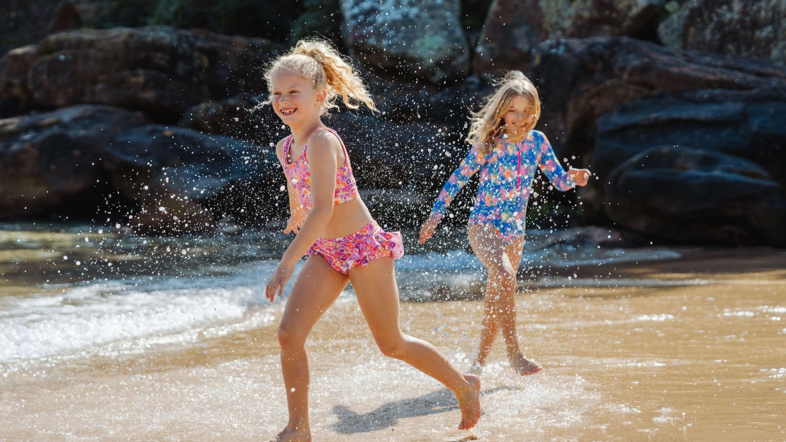 girls splashing at waters edge at the beach wearing ocean tales